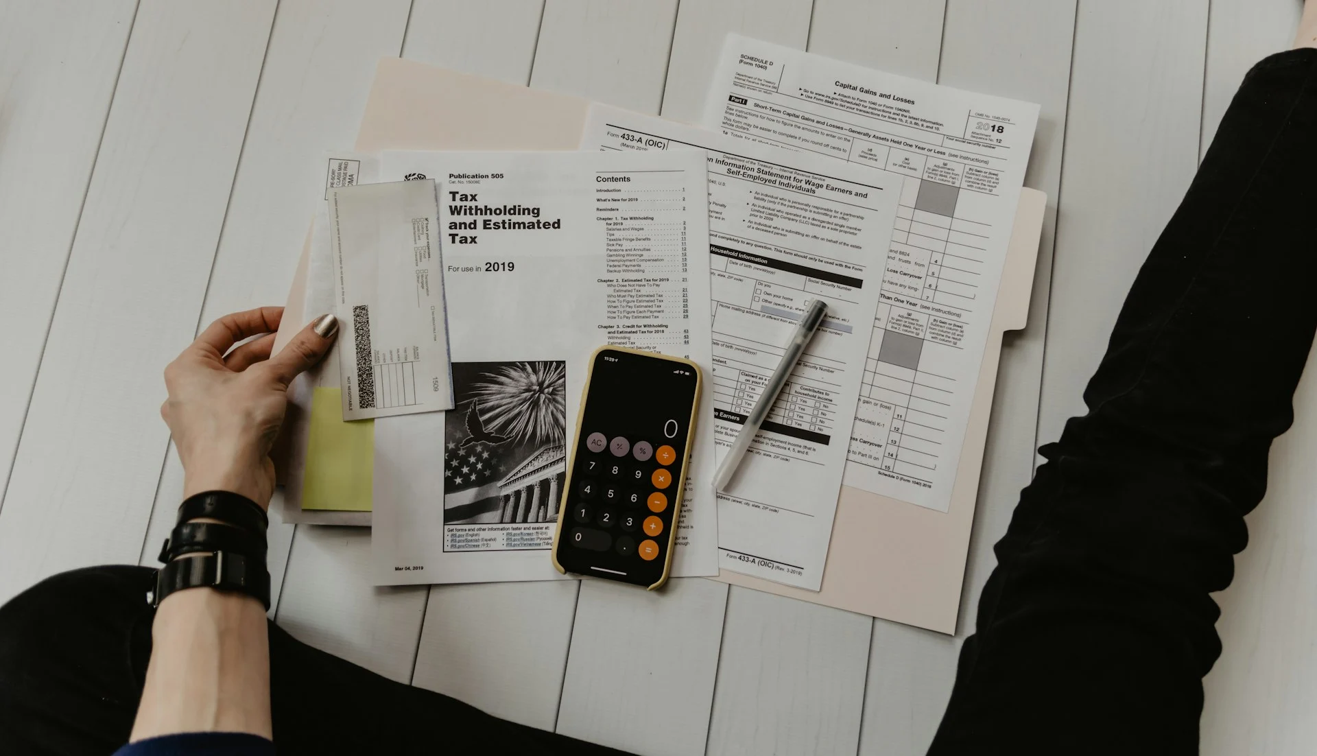 Hands reviewing financial documents with a calculator and phone