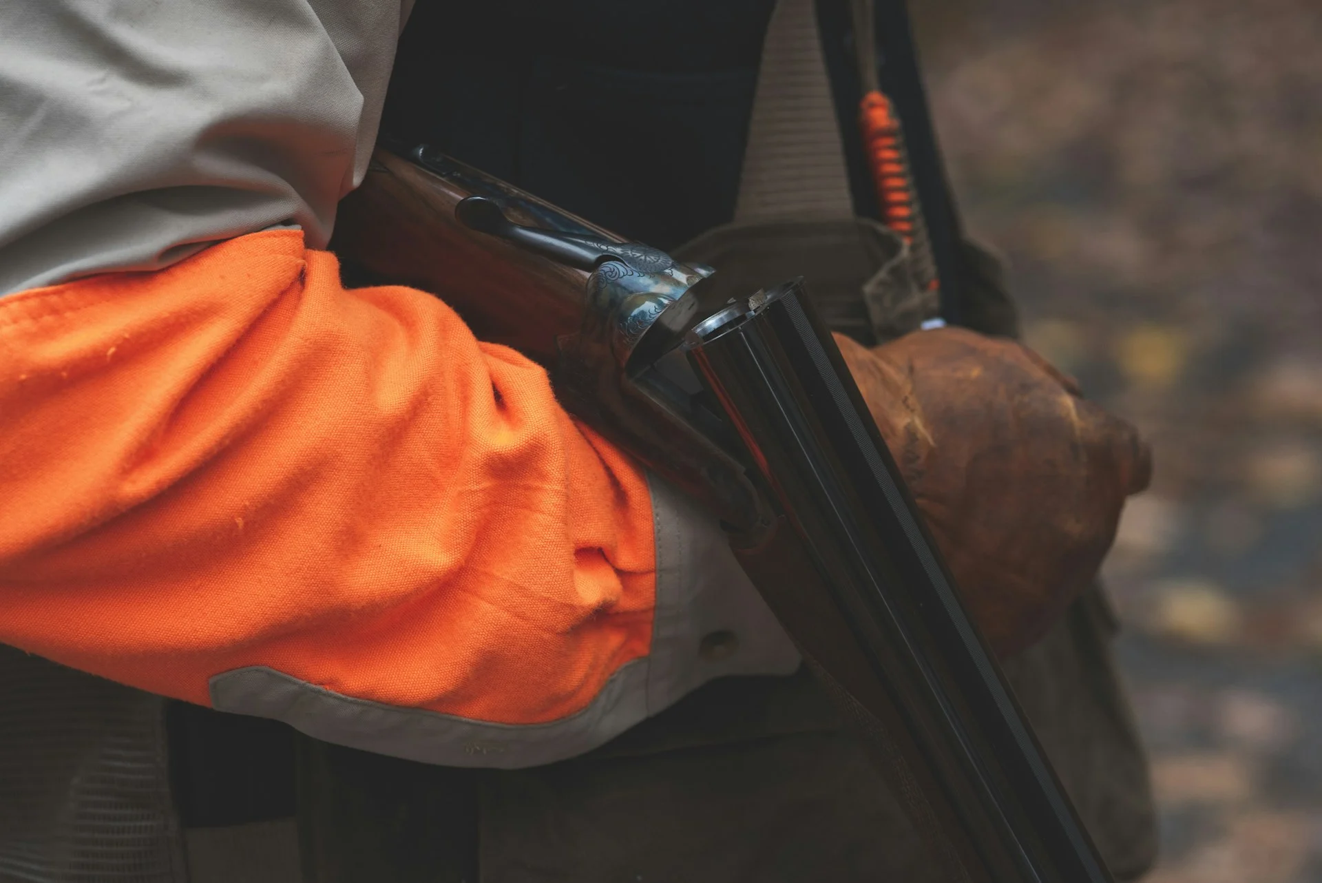 Hunter in blaze orange loading a shotgun
