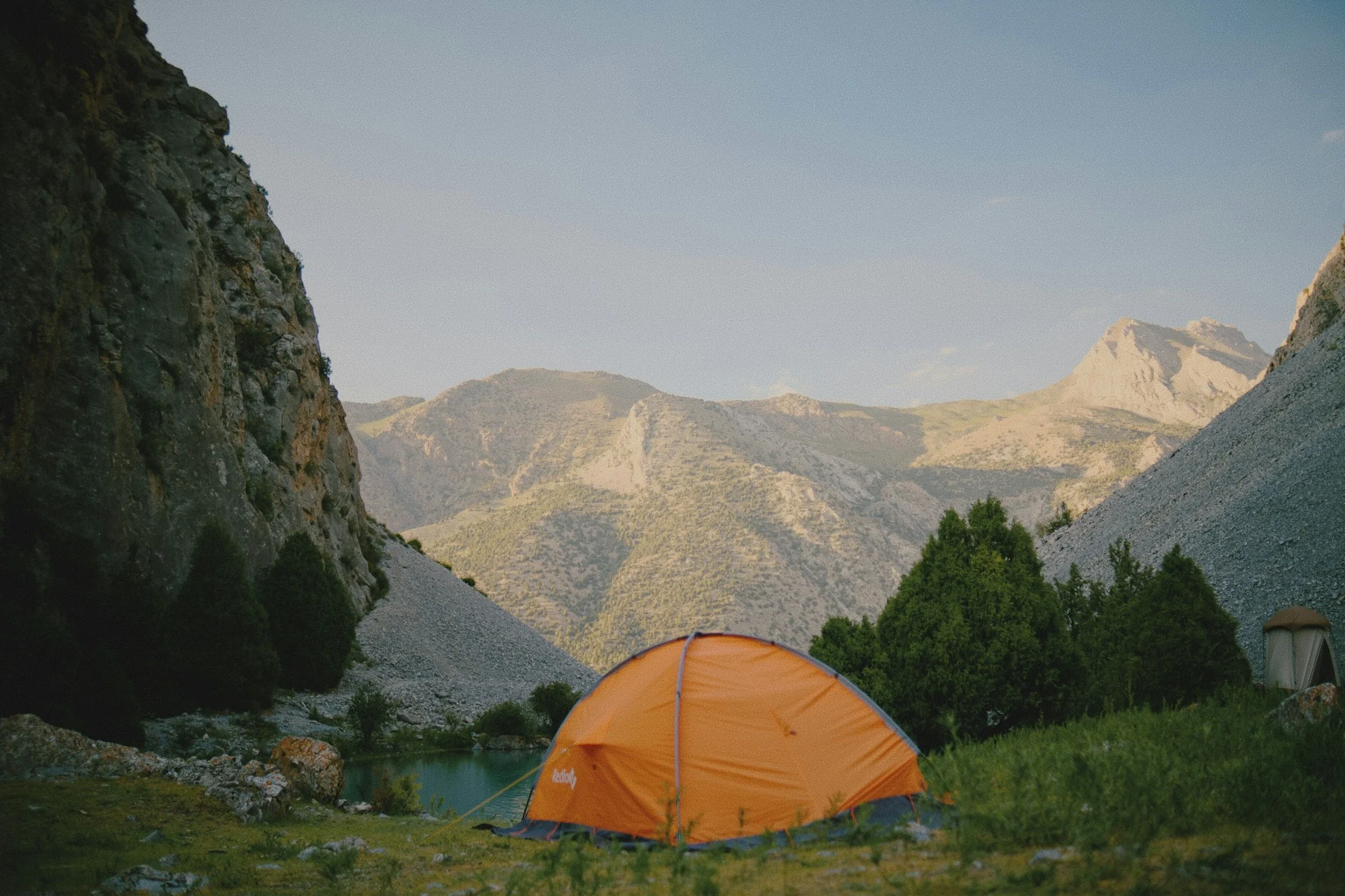Orange tent in a mountain valley