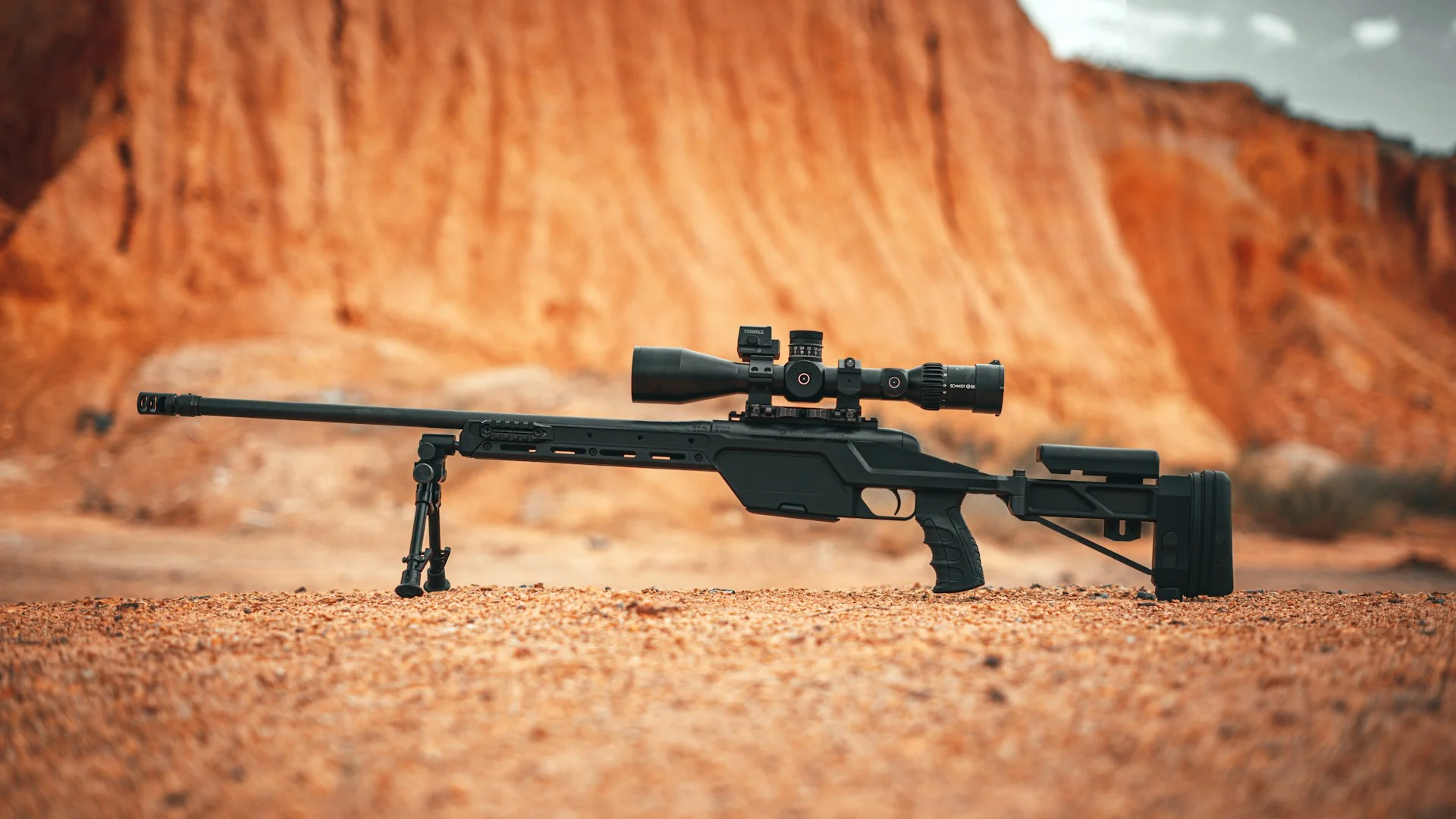 Bolt-action precision rifle resting on red rock