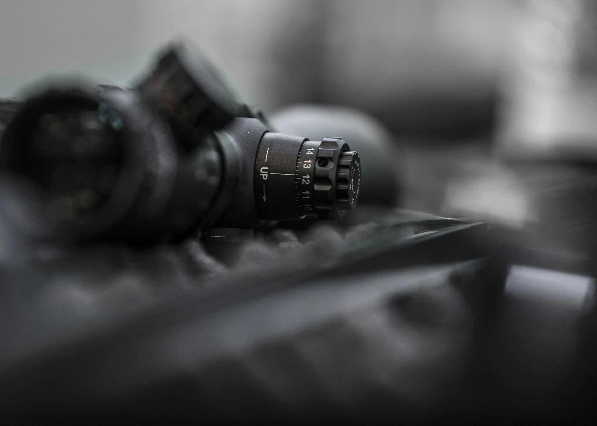 Black-and-white close-up of a rifle optic