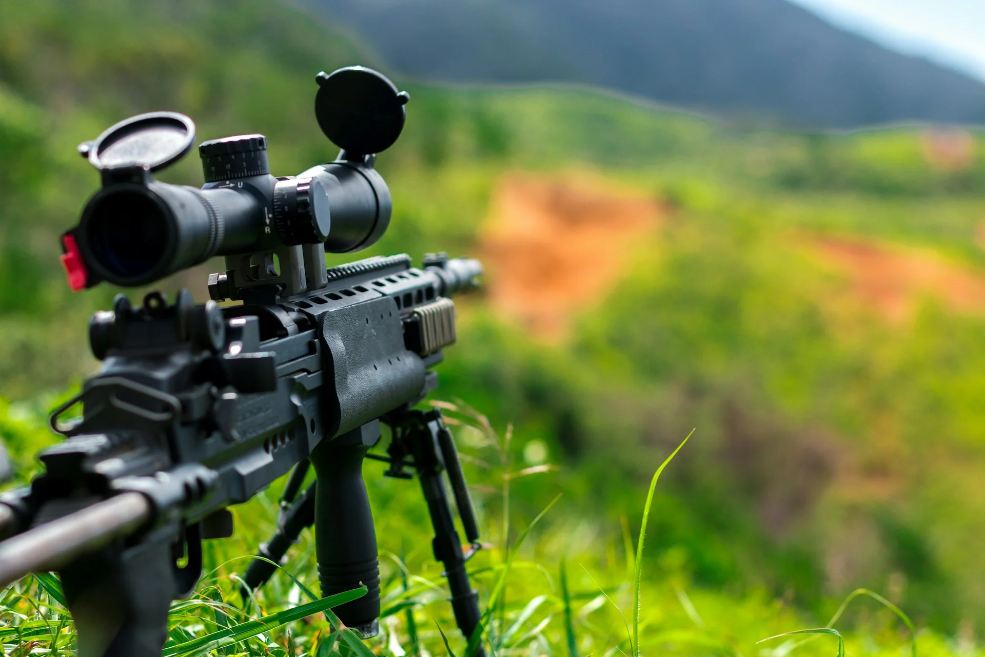 Scoped rifle on a bipod in a green field