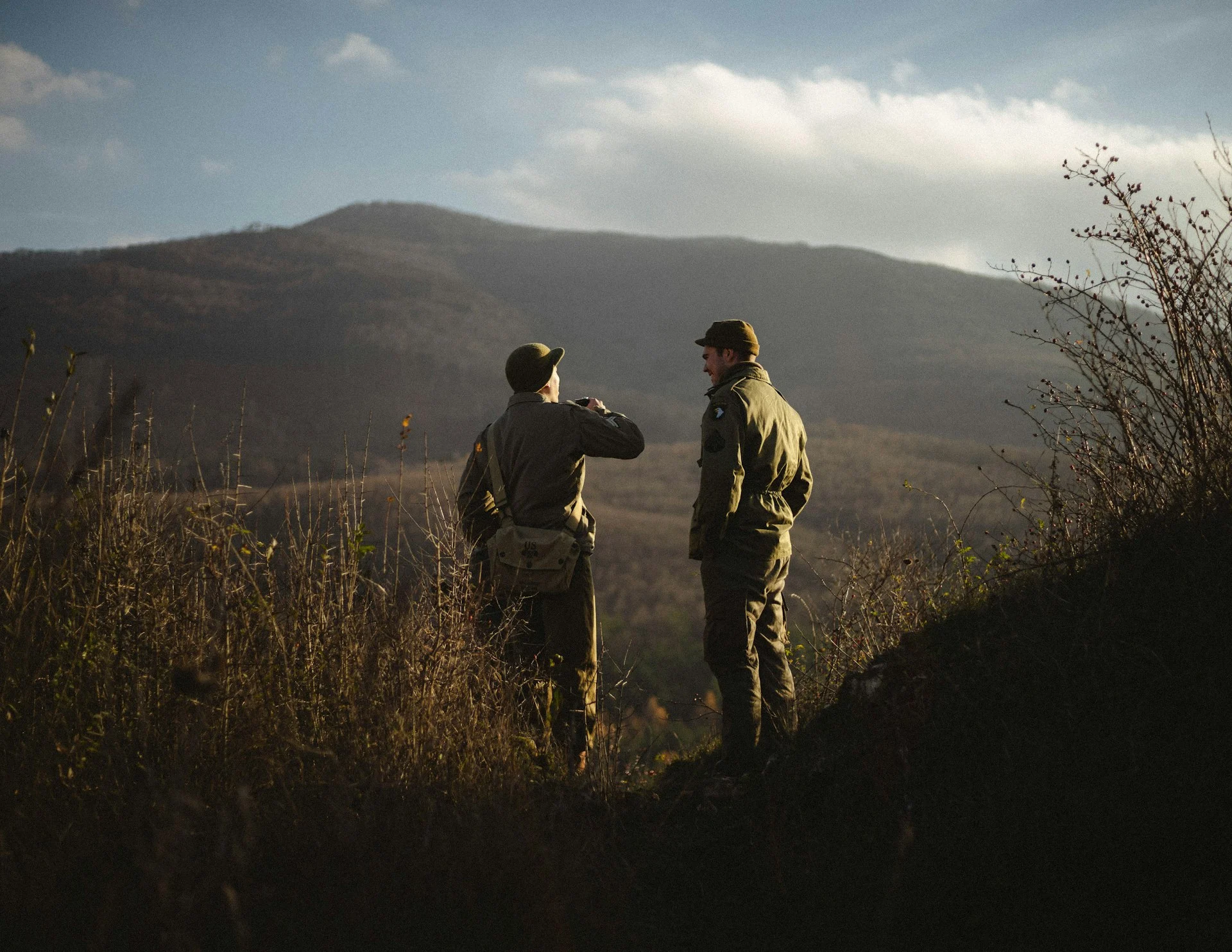 Two hunters standing on a grassy hillside